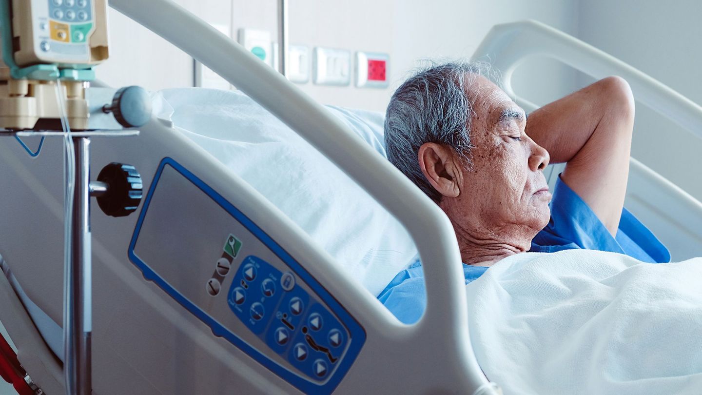 Basınç ülserleri: Yaşlı bir adam gözleri kapalı bir hastane yatağında yatıyor.
