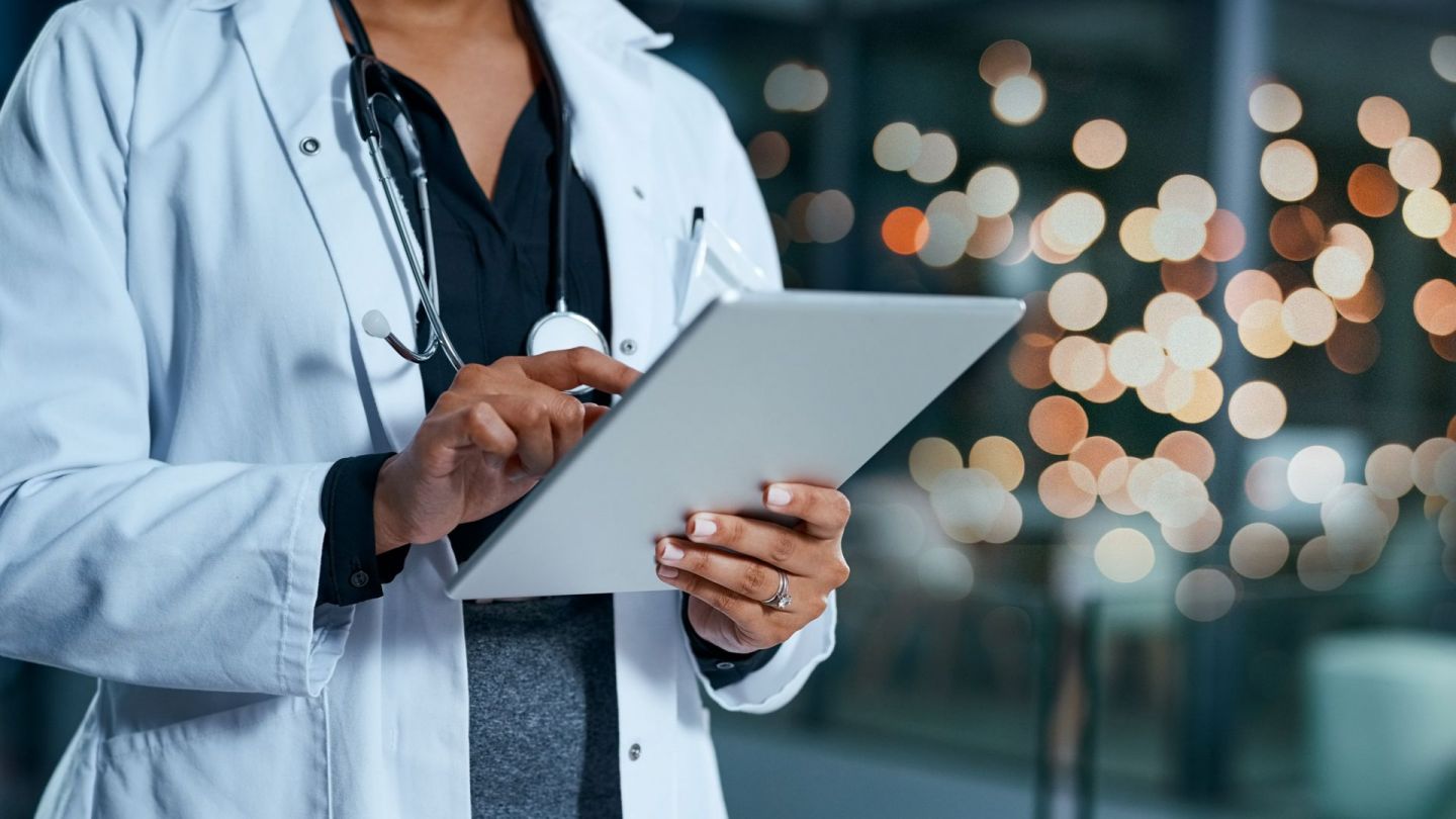 Dijital tıp: Bir doktor bir elinde tablet tutuyor ve diğer eliyle ekrana dokunuyor.