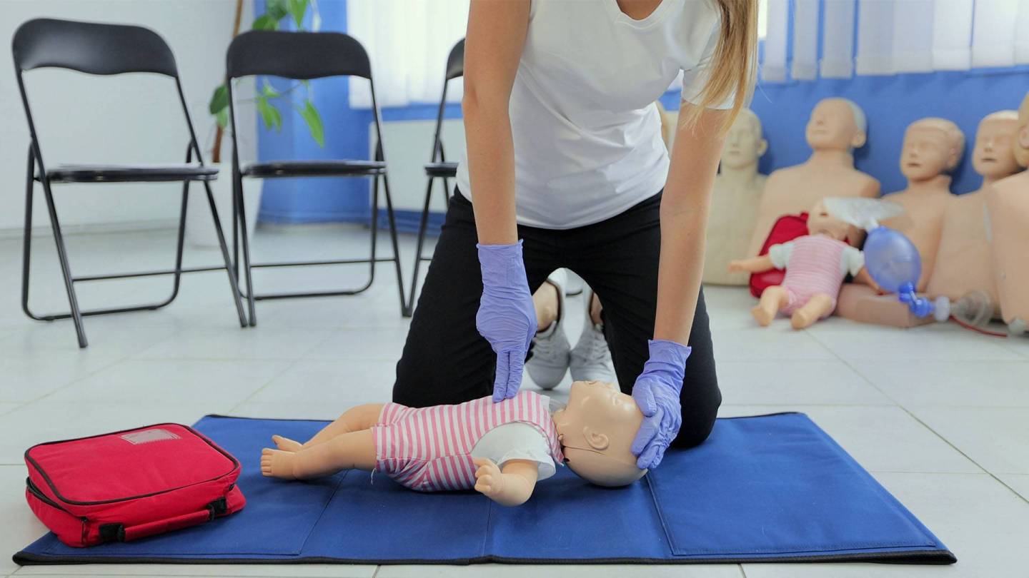Frau übt Wiederbelebung an einer Säuglings-Puppe