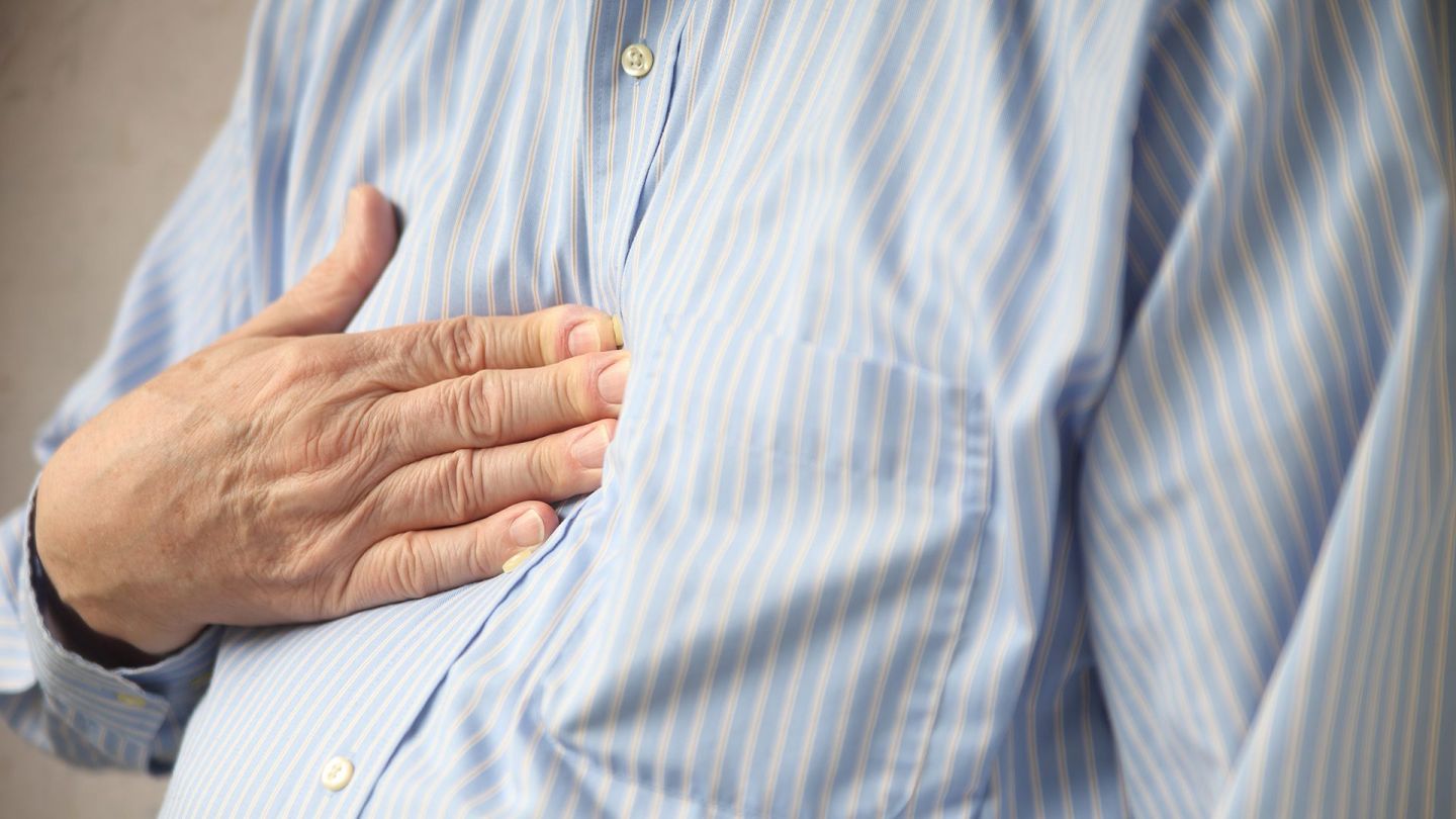 Gastroösophageale Refluxerkrankung: Eine Person drückt ihre rechte Hand auf den Brustkrob.