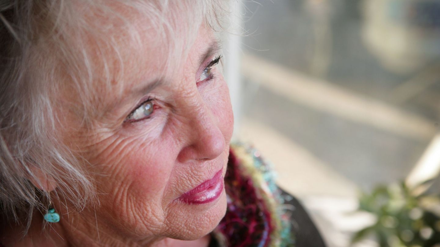 Grauer Star (Katarakt): Eine ältere Frau mit grünblauen Augen schaut in die Ferne.