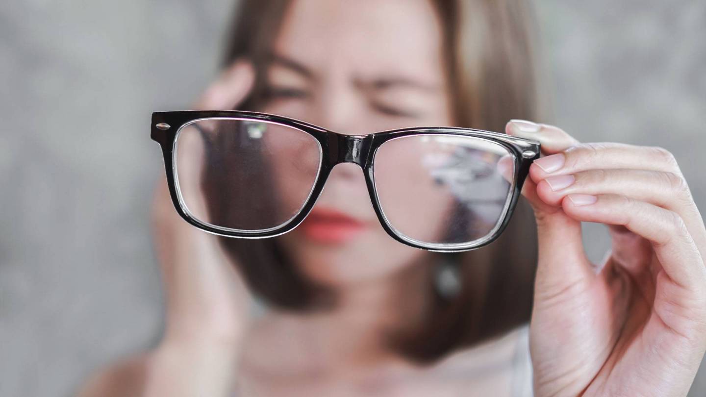 Blurred face of a woman who appears dazed. She is wearing glasses in the foreground that are in sharp focus.