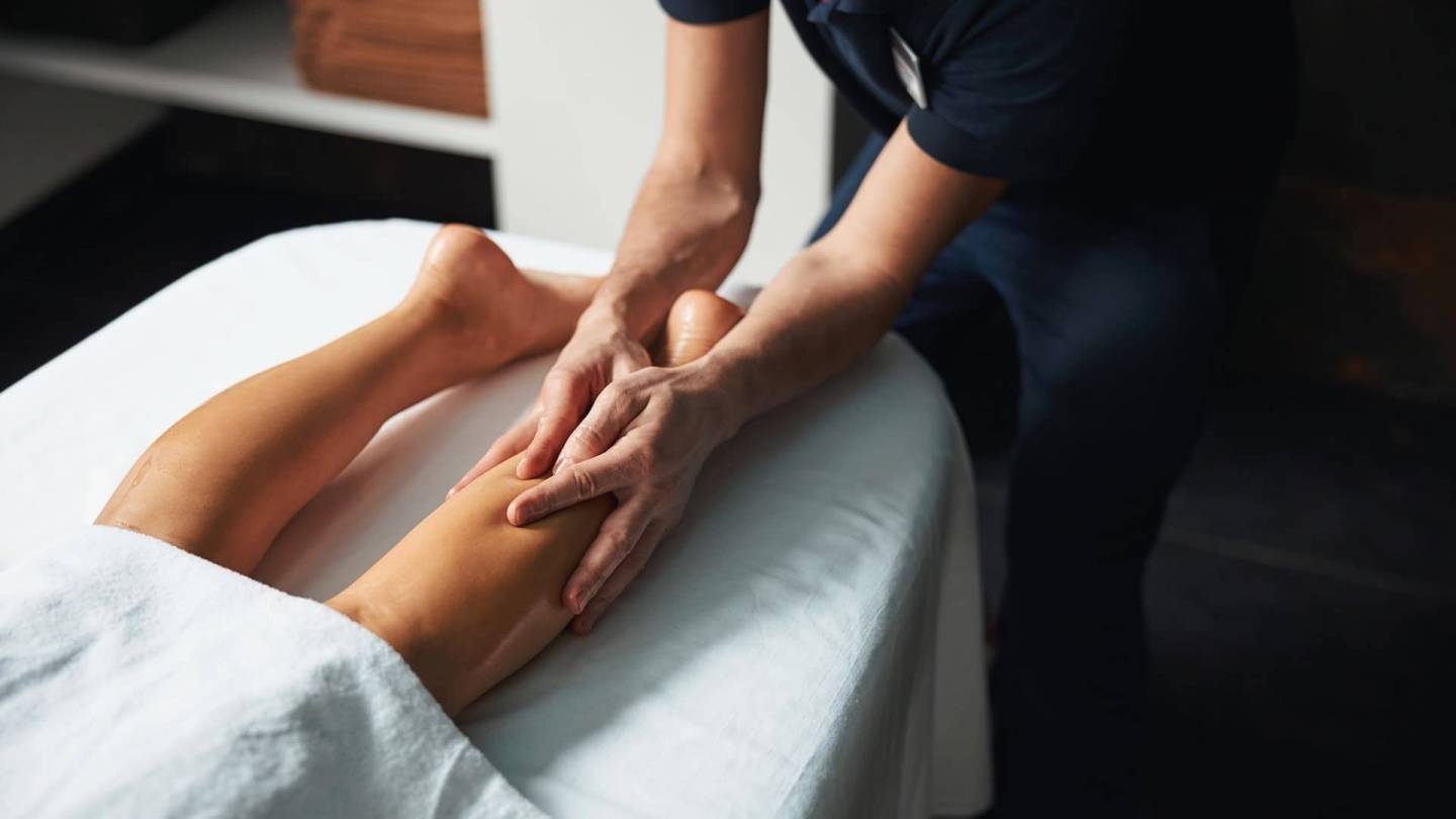 Bir fizyoterapist, tıkanmış lenflerin dışarı akabilmesi için hastanın bacaklarına masaj yapıyor.