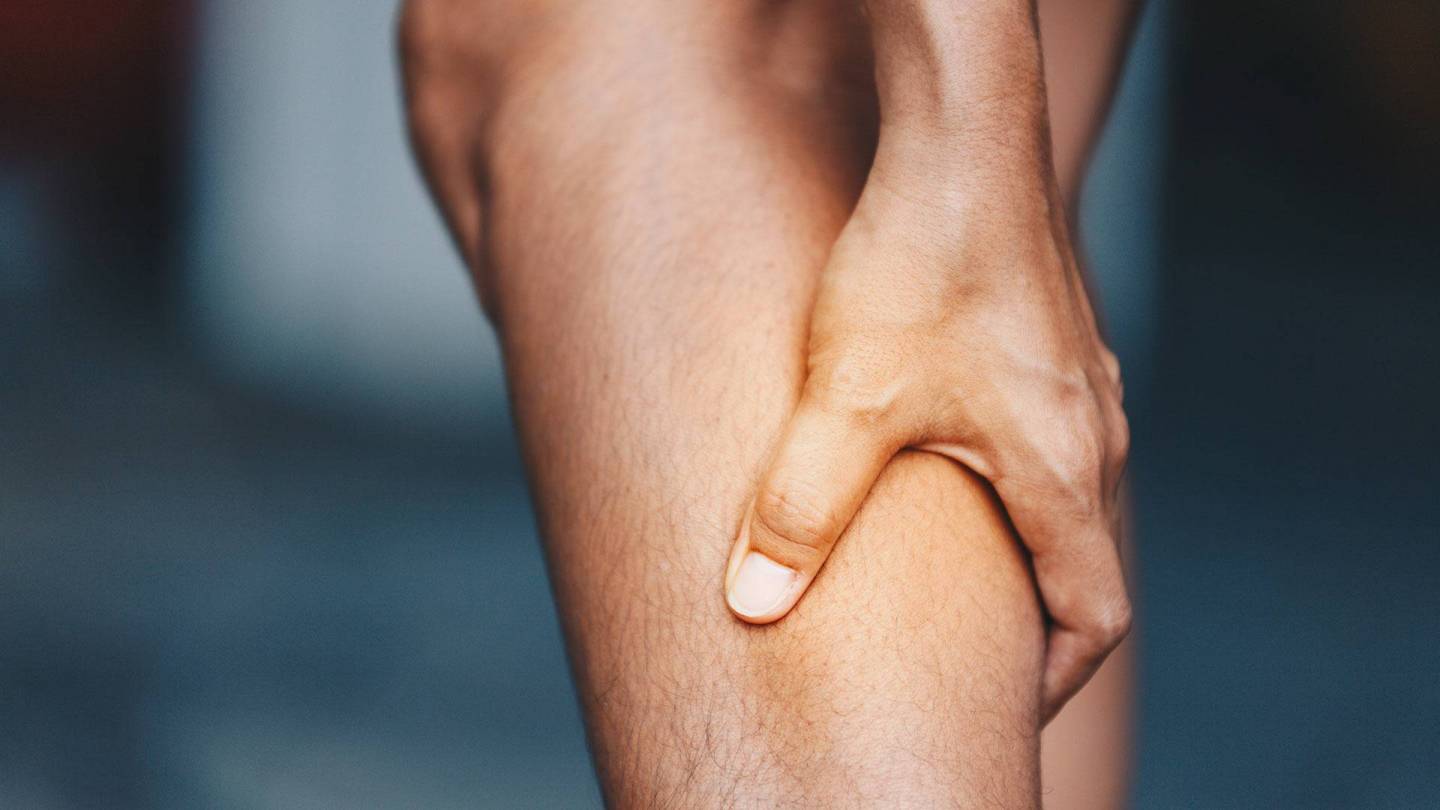 A hand is grasping a calf muscle.