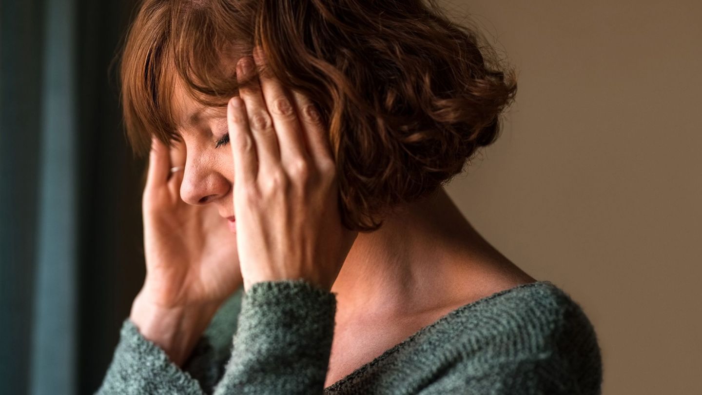 Migraine: woman holding her head in both hands.