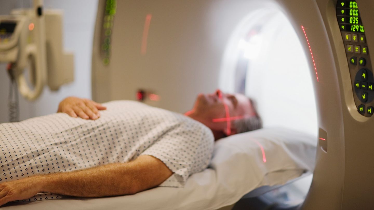الورم النقوي المتعدد: رجل يرقد في أنبوب التصوير بالرنين المغناطيسي. ويمر شعاعان من الليزر الأحمر أعلى وجهه.