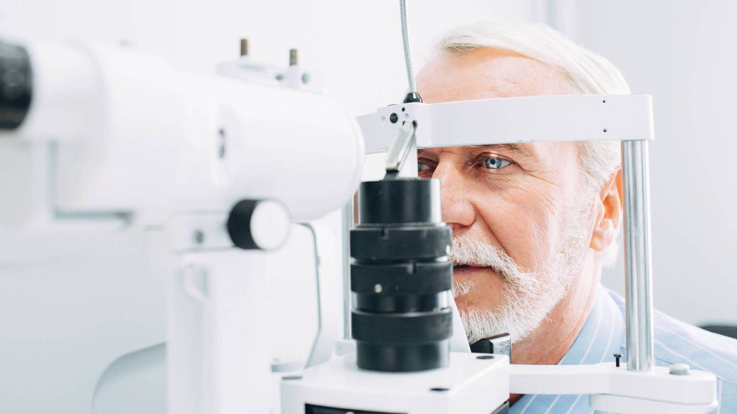 Arzt untersucht das Auge eines Mannes mit der Spaltlampe