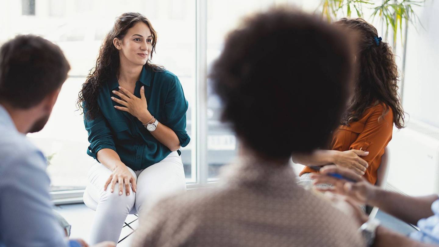 A woman sits in a small discussion group