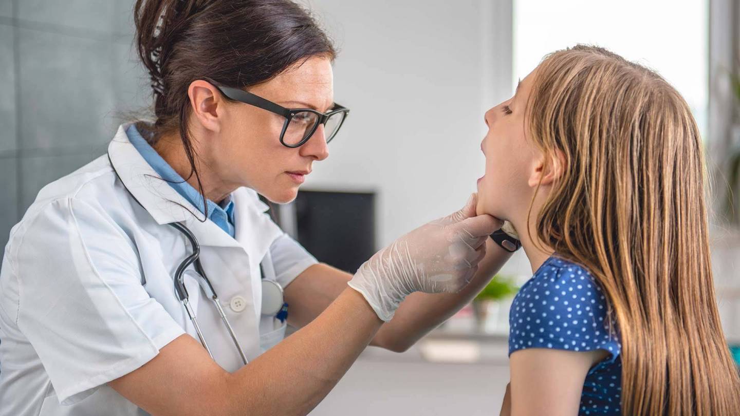 Behandlungszimmer: Eine Ärztin schaut in den geöffneten Mund eines Mädchens.