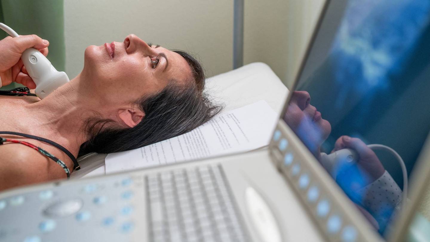 Frau wird am Hals mit Ultraschall untersucht