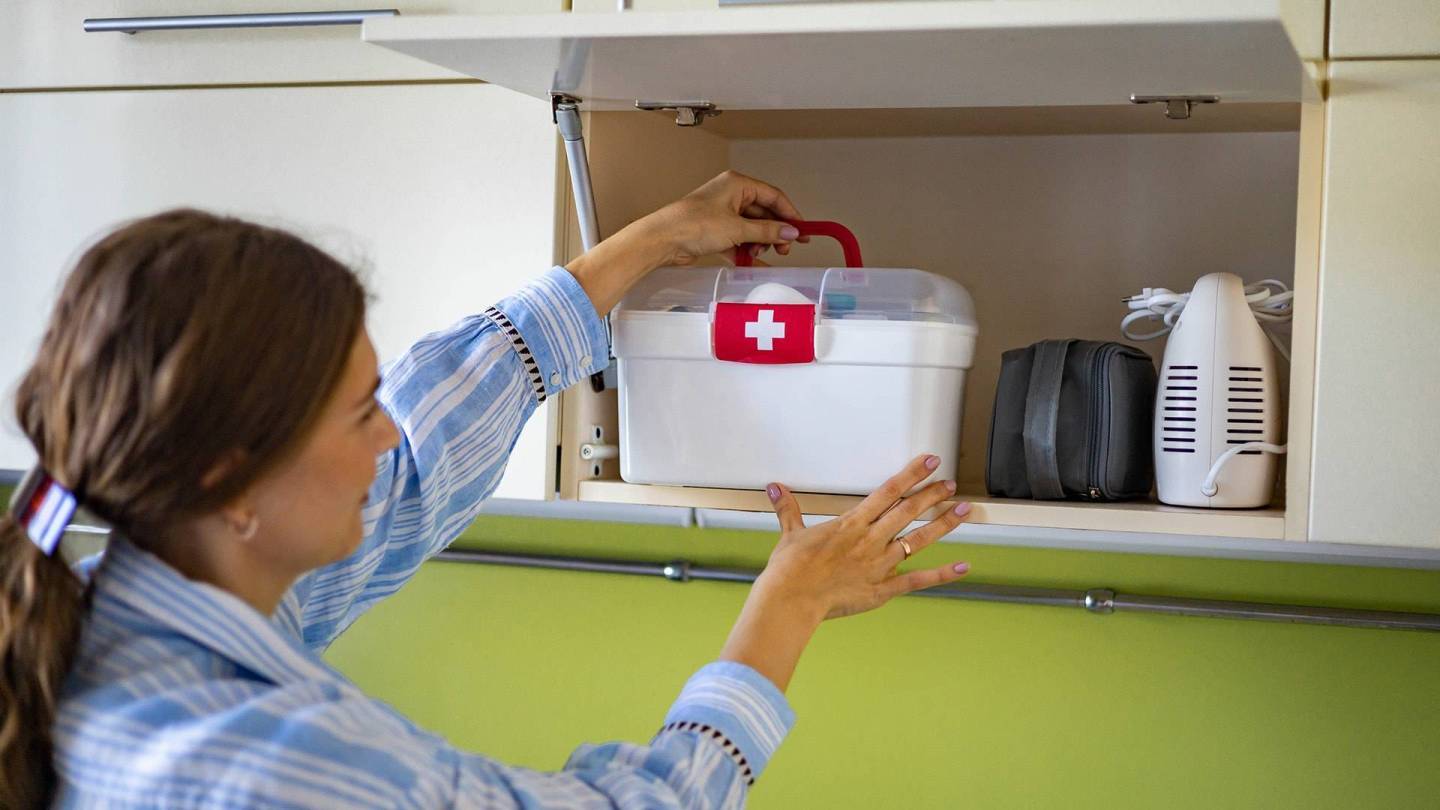 Eine Frau stellt einen Erste Hilfe Koffer mit Medikamenten in einen Kühlschrank