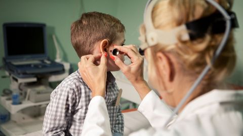Akute Mittelohrentzündung: Eine Ärztin schaut in das Ohr eines Jungen.