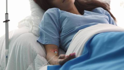 A woman receiving an infusion in a hospital bed
