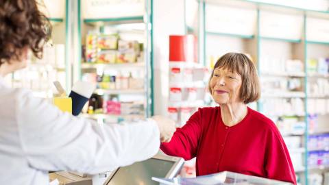 Frau kauft Arzneimittel in einer Apotheke.