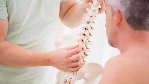 Slipped disc: doctor showing a man the model of a spinal column.