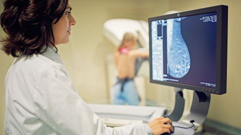 Breast cancer: doctor sitting in front of a screen. She is examining the X-ray of a woman’s breast on the screen.