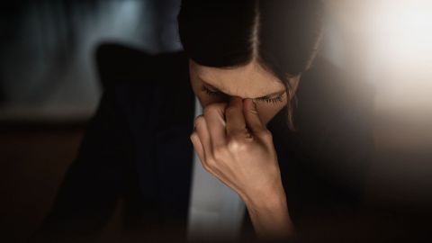 Burnout: woman looking down with hand between nose and forehead.