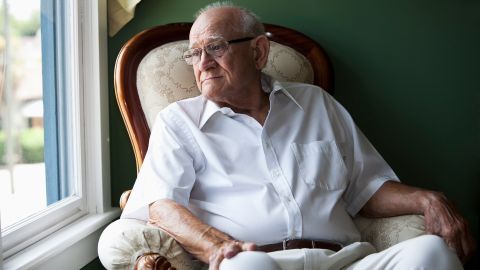 Chronic myeloid leukemia (CML): older man sitting on a chair looking out of the window. He looks thoughtful.