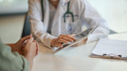 حماية البيانات: طبيب يعرض لمريضة شيئًا على الكمبيوتر اللوحي.