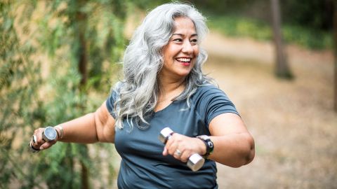 Type 2 diabetes: woman holding dumbbells in both hands, actively engaged in sports and smiling.