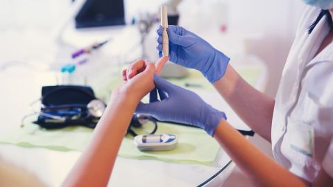 Diabetes Typ 1: Eine Ärztin entnimmt Blut aus der Fingerkuppe einer Frau, um den Blutzucker zu messen.