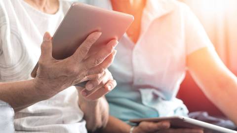Zwei ältere Frauen betrachten den Bildschirm des Tablets, das die eine Frau in den Händen hält.