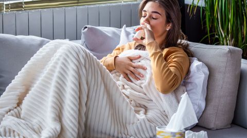 Woman with a common cold using a nasal spray.