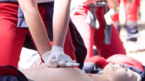 A first aider gives heart compressions to a training mannequin.
