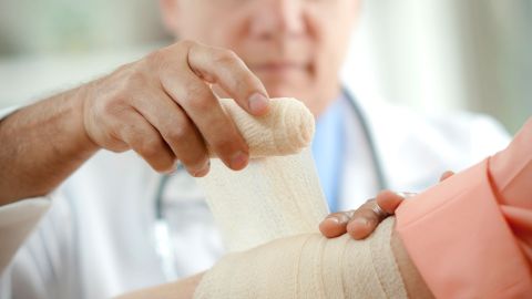 Boils and carbuncles: doctor wrapping a gauze bandage around an arm.