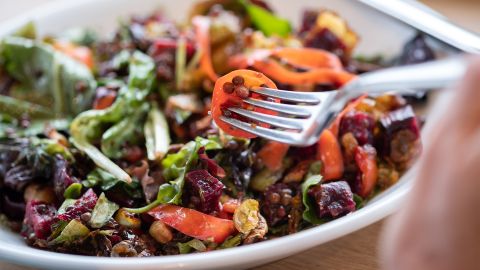 Healthy diet: a person poking a fork into a brightly colored lentil salad.