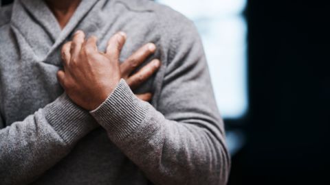 Учащенное сердцебиение: мужчина обеими руками держится за сердце.