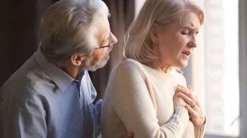 Herzrhythmus-Störung: Eine Frau fasst sich mit beiden Händen an den Brustkorb.