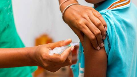 A child is being vaccinated with an injection into the upper arm.