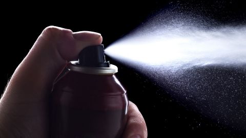 Contact allergy: thumb pressing nozzle on contact spray bottle; spray released.