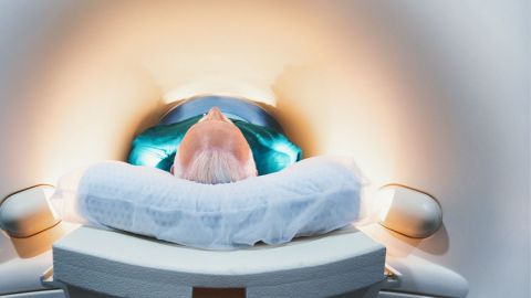 Man lying on his back in a narrow, brightly lit tube for an MRI scan.