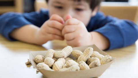 Food allergy: a boy sitting at a table in front of a bowl of peanuts.