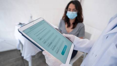 Hastane: Ön planda hasta verilerini gösteren bir tablet, arka planda bir kadın hasta.