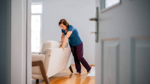 A woman is feeling dizzy and leaning on a sofa to support herself.