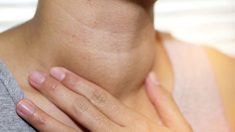 Schilddrüsenunterfunktion: Eine Frau fasst sich an den Hals.