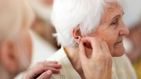 Older woman having her hearing aid adjusted.