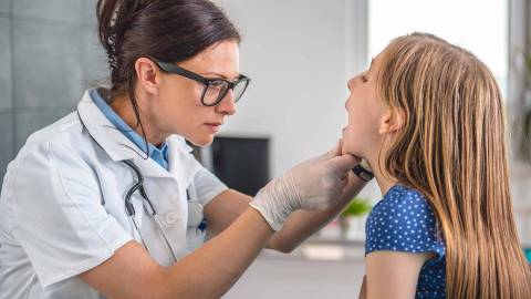 Медицинский кабинет: врач осматривает горло девочки.