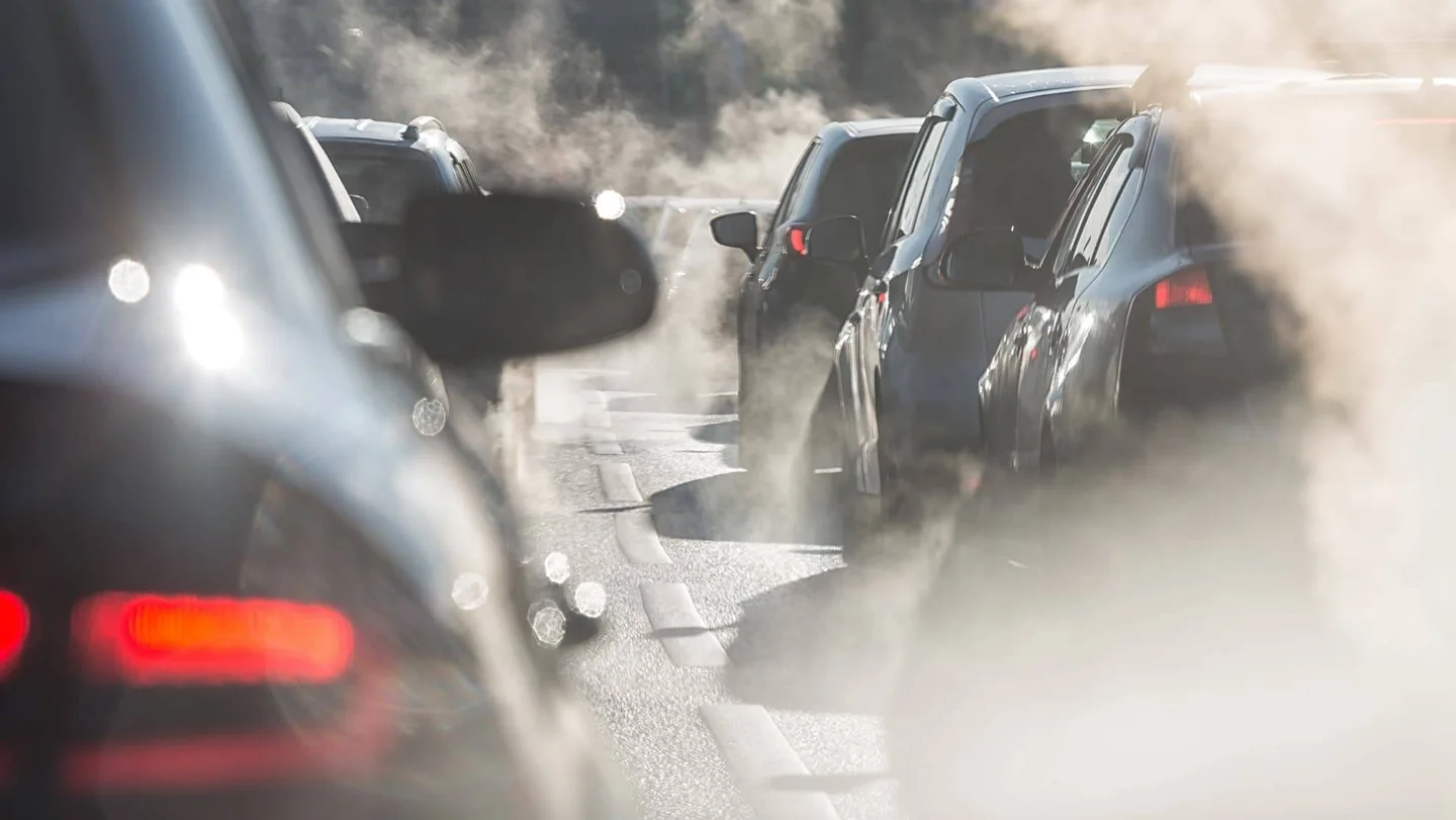 Nahaufnahme von Autos im stockenden Verkehr und Abgaswolken.