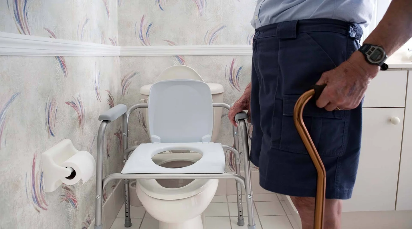 Mann mit Gehstock vor einer behindertengerechten Toilette