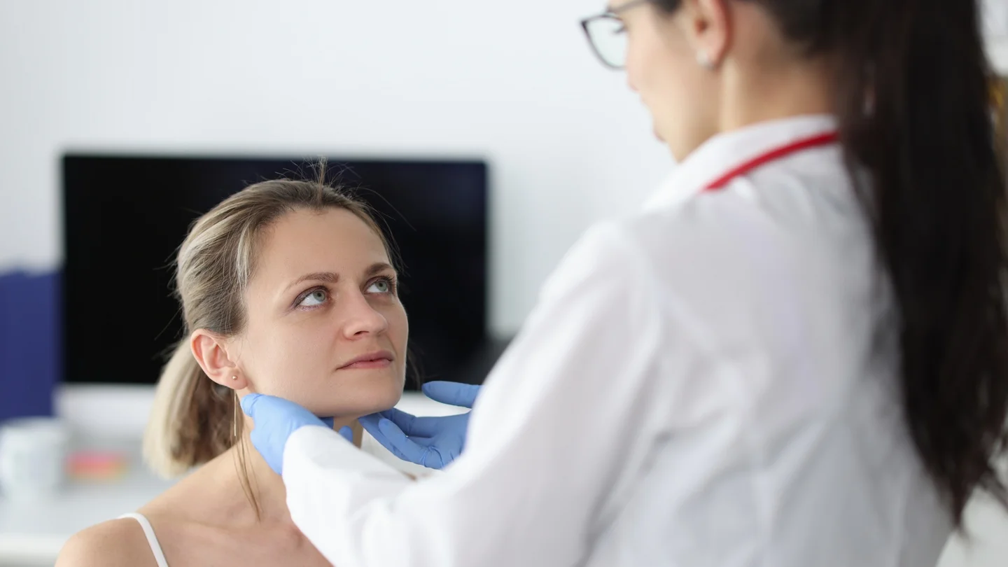 Ärztin tastet die Bereiche der Unterkieferspeicheldrüse einer Patientin ab.