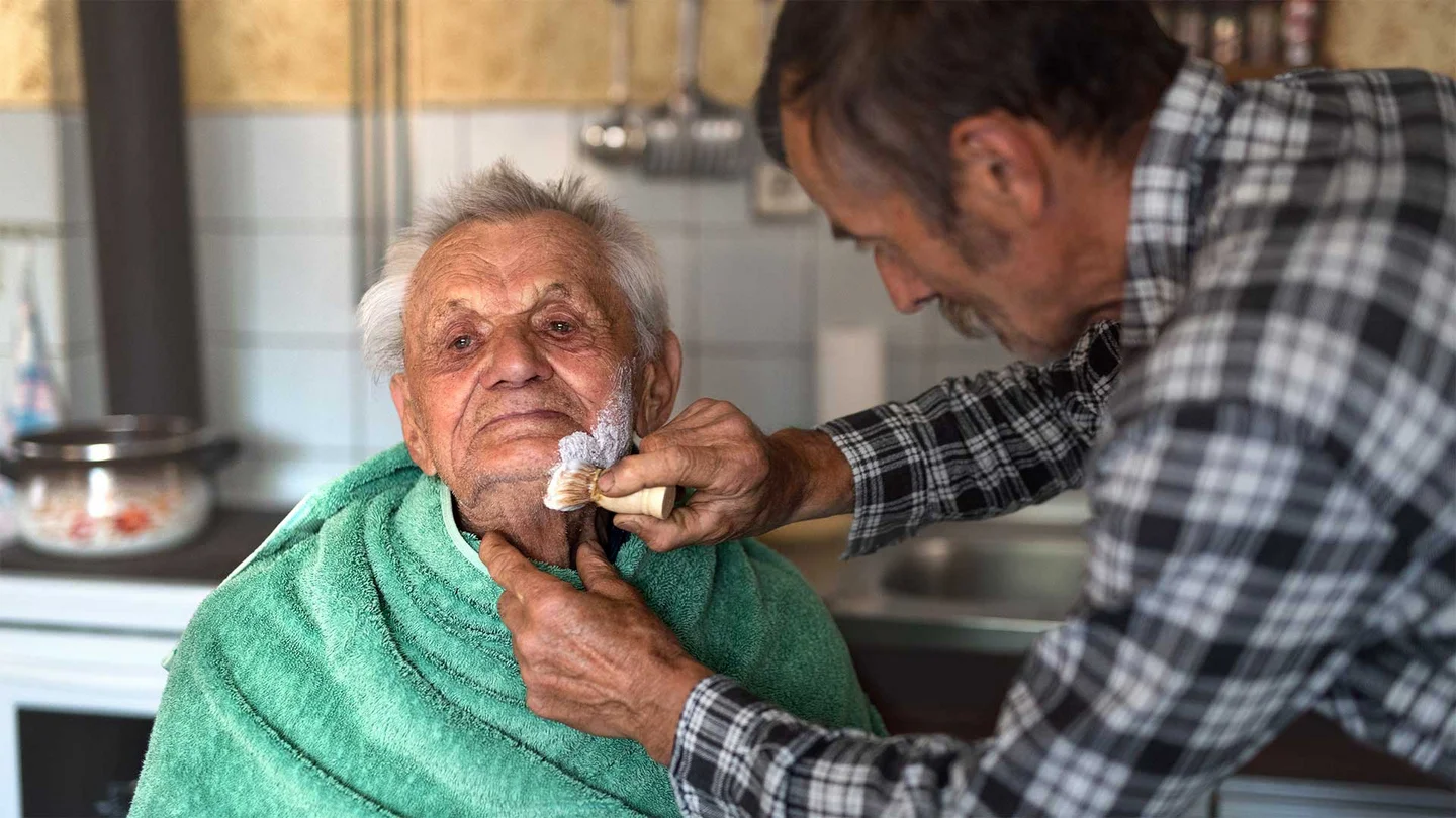 Ein älterer Herr wird rasiert. 