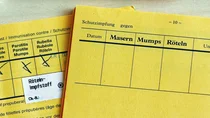 Zwei aufgeschlagene Impfausweise, davon einer mit eingetragener Impfung gegen Mumps, Masern und R&ouml;teln.
