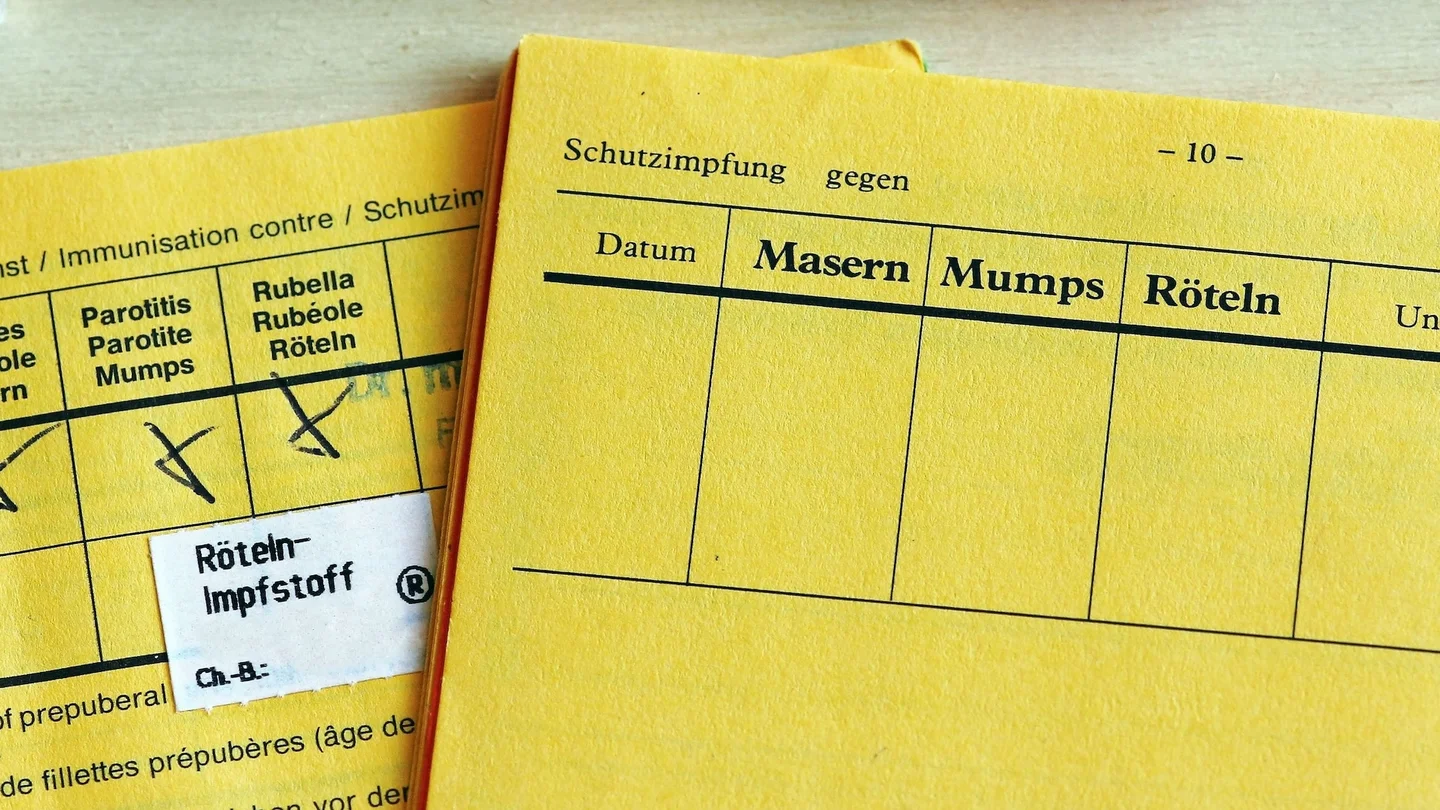 Zwei aufgeschlagene Impfausweise, davon einer mit eingetragener Impfung gegen Mumps, Masern und R&ouml;teln.